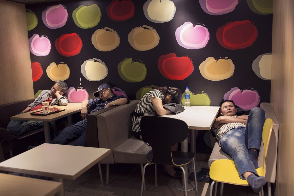 In this Oct. 30, 2015 photo, a group of people sleep at night in a 24-hour McDonald’s branch in Hong Kong. The recent death of a woman at a Hong Kong McDonald’s, where her body lay slumped at a table for hours unnoticed by other diners, has focused attention on the city’s “McRefugees” down and out people who spend their nights the fast food outlet’s 24-hour branches because they’ve nowhere anywhere else to go. (AP Photo/Vincent Yu)
